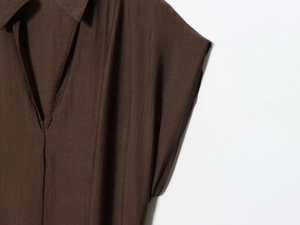 Gros plan détaillé du col en V et du tissu marron foncé texturé de la robe