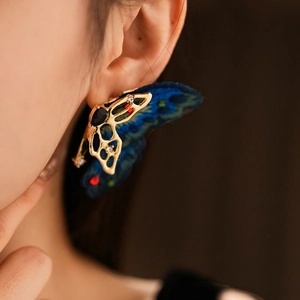 Vintage gold butterfly earrings with blue embroidery and crystals on female model