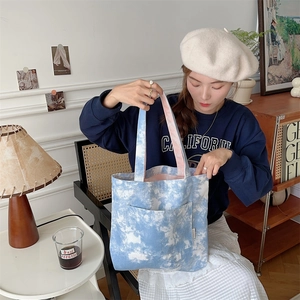 Dettaglio ravvicinato della borsa tote in tela tie-dye blu con etichetta e tasca