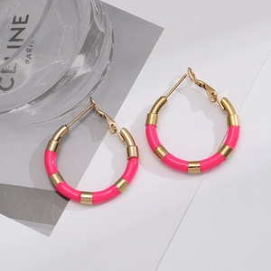 Detail shot of round enamel hoop earrings in pink and gold stripes with secure clip-on clasps