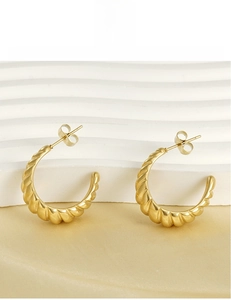 Detail of 18K gold plated spiral C-hoop earrings with shell texture on silk background