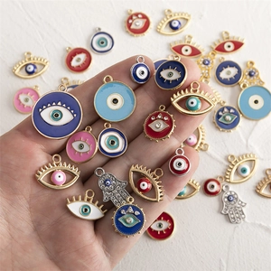 Mix of colorful enamel evil eye and Hamsa hand pendants with rhinestones in hand