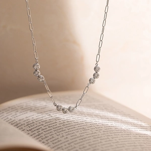 Elegant paperclip chain necklace with nine bezel-set white zircons over an open book