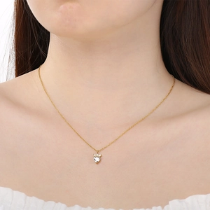 Close-up of golden heart pendant necklace with a clear zircon stone on woman neck