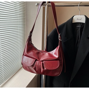 Detail of dark red glossy leather shoulder bag with pleated texture and dual front pockets