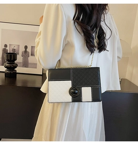 Detail of a black and white quilted shoulder bag with metal chain and turn-lock closure