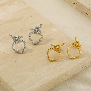 Détails de boucles d'oreilles nœuds torsadés dorés et argentés sur support marbre