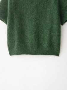 Dettaglio del maglione in maglia verde scuro con trama morbida e bordo a costine fini