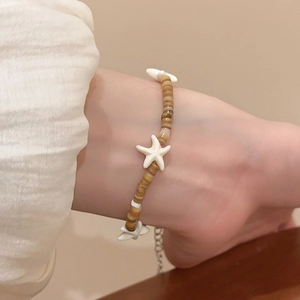 Detail of bohemian bracelet with brown wooden beads and white starfish charms