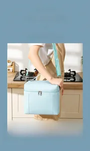 Blue insulated lunch bag with adjustable shoulder strap shown in a modern home kitchen