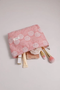 Detailed interior of pink cotton linen floral cosmetic bag with brushes and makeup items