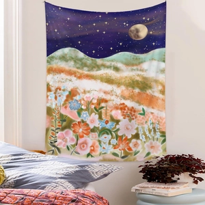 Dreamy mountain moon phase tapestry with flowers hanging in a cozy bedroom