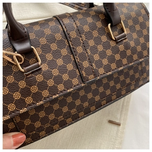 Macro detail of brown lychee texture leather with golden clover patterns and hardware