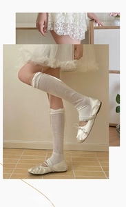 Detail of balletcore ribbed leg warmers with delicate ribbons and satin flat shoes