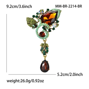 Vintage gold alloy brooch with brown waterdrop glass gems and rhinestones on white backdrop