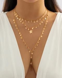 Dettaglio collana dorata a più strati con pendenti a stella e nappa a Y dal design moderno