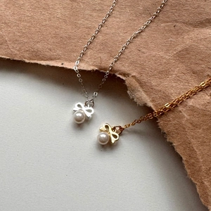 Detail of silver and gold bow pearl necklaces on brown kraft paper background