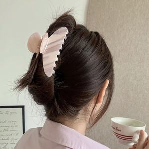 Detail view of pink and white marble acetate hair claw clip worn by a model