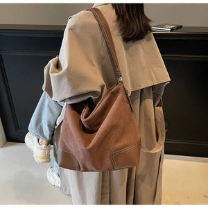 Detail of brown suede tote bag featuring reinforced leather patch and white contrast stitching