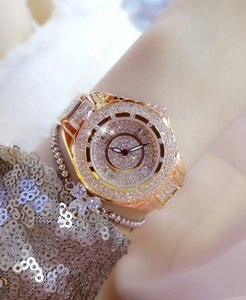 Close-up of luxury gold women's watch with shimmering diamonds and matching silver bracelet