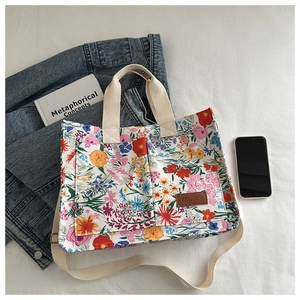 Flat lay of floral canvas tote bag with shoulder strap next to a denim jacket
