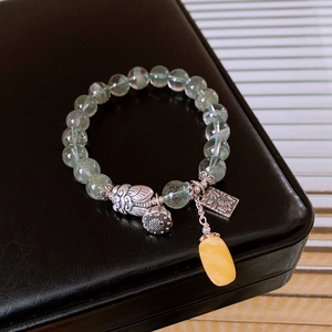 Detail of S925 silver lotus pod bracelet with green phantom crystals and amber charm
