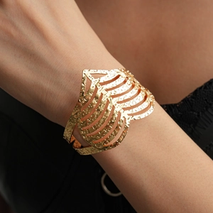 Detailed view of wide gold open cuff bracelet with hollow heart pattern and hammered texture