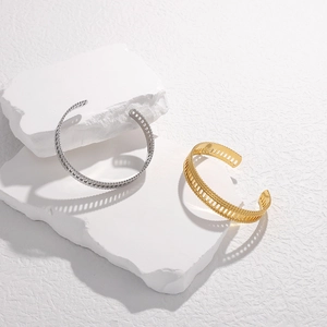 Detail of open cuff gold and silver stainless steel bracelets with hollow texture and beads