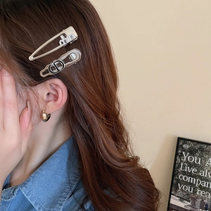 Detail showing Y2K style silver and gold metal hair clips with rhinestones on brown hair