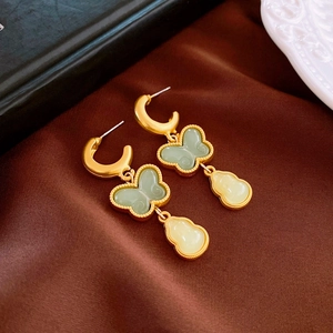 Detail of vintage gold butterfly earrings with green stones on a brown silk background