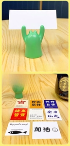Front and back views of a green resin animal business card holder on a wooden desk