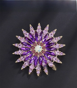 Macro shot of purple crystal sunflower brooch with golden metal and iridescent center