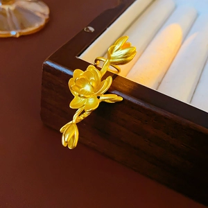 Close-up of matte gold lotus earrings on a wooden jewelry box with a velvet interior