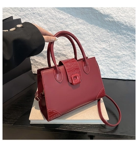 Detail of burgundy PU leather handbag with crocodile pattern texture and dual handles