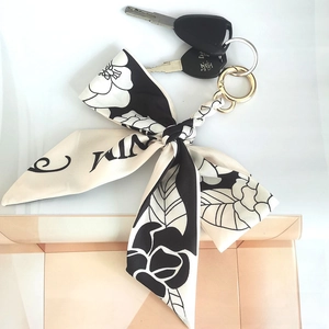 Close-up of black and white camellia floral silk ribbon keychain with gold ring
