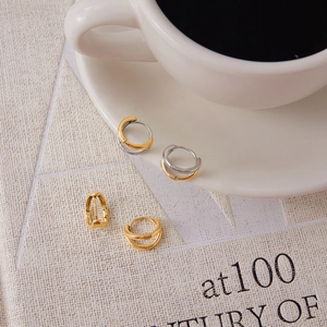 Detailed close-up of 18K gold stainless steel layered hoop earrings set on aesthetic prop