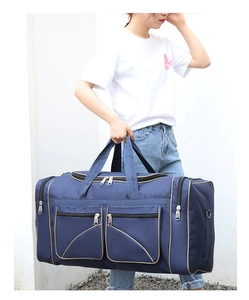 Close-up of blue nylon travel bag with gold trim, zipper pockets and sturdy side handle