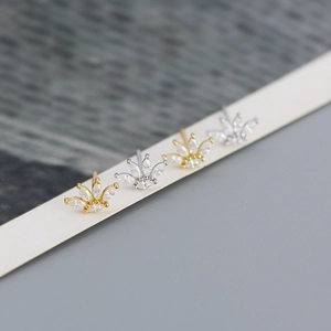 Macro shot of crown shaped zircon stud earrings in gold and silver finish details