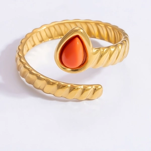 Detail of gold twisted band ring featuring a red teardrop-shaped natural stone gemstone