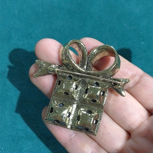 Golden gift box brooch with rhinestone accents and secure safety pin for festive clothing