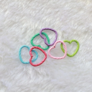 Detail of heart-shaped metal jump rings in assorted vibrant colors for DIY jewelry making