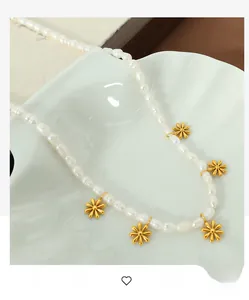 Close-up of fresh water pearl necklace with gold daisy floral pendants on a ceramic tray