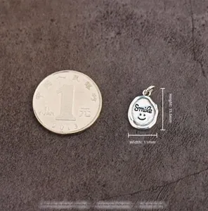 Macro shot of 925 sterling silver smile pendant next to a coin for size reference