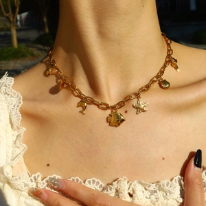 Detail of 18K gold plated necklace with starfish and sea shell charms worn by a model