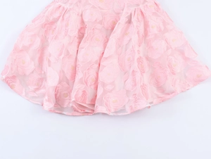Détail du tissu jacquard à roses roses et de la broderie florale sur cette mini robe