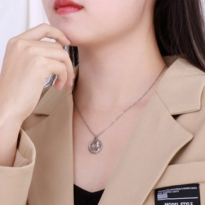 Close-up of a model wearing a vintage silver coin pendant on a delicate chain necklace
