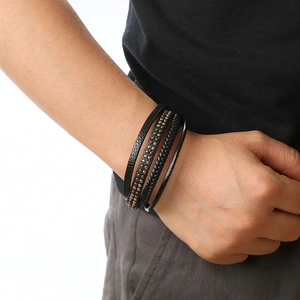 Close-up of a multi-layer black leather bracelet with braided bands and metal studs detail