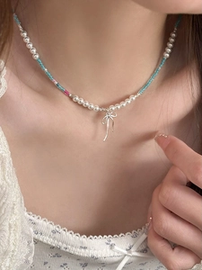Vue détaillée du collier de perles colorées avec pendentif nœud argenté sur mannequin