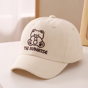 Close-up of a cream cotton baseball cap featuring a cute embroidered bear and text