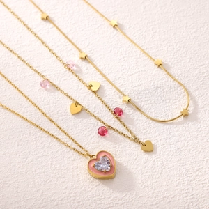 Layered gold heart and star necklace featuring vibrant red and pink crystal beads